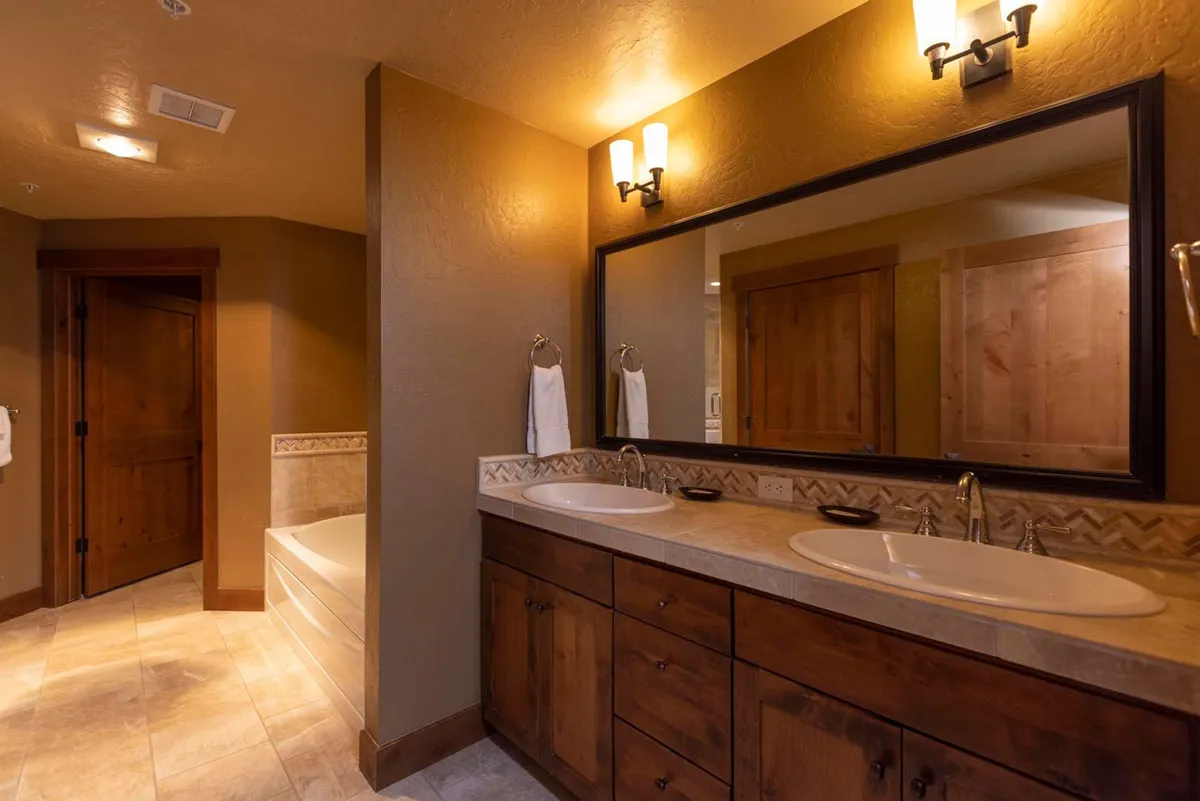 This bathroom features a double sink vanity, large mirror, wooden cabinetry, and a bathtub—all creating a serene, spa-like atmosphere for relaxation and self-care.